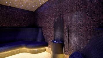 Un spa moderno con un muro cubierto de mosaicos, suelo con calefacción y una zona de estar.