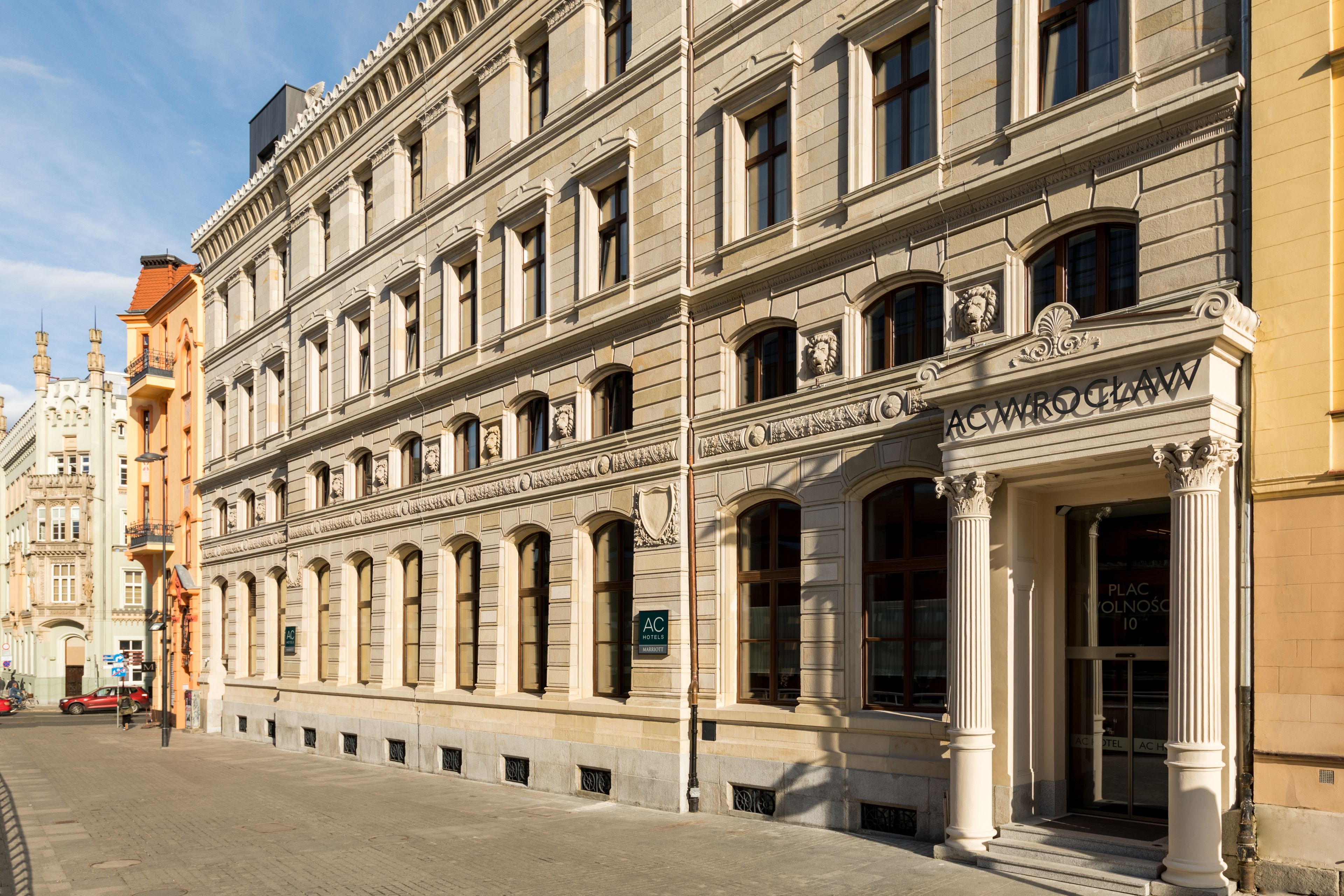 Edificio histórico de arquitectura clásica, que destaca por su entrada con columnas y un cartel que indica que es un hotel.