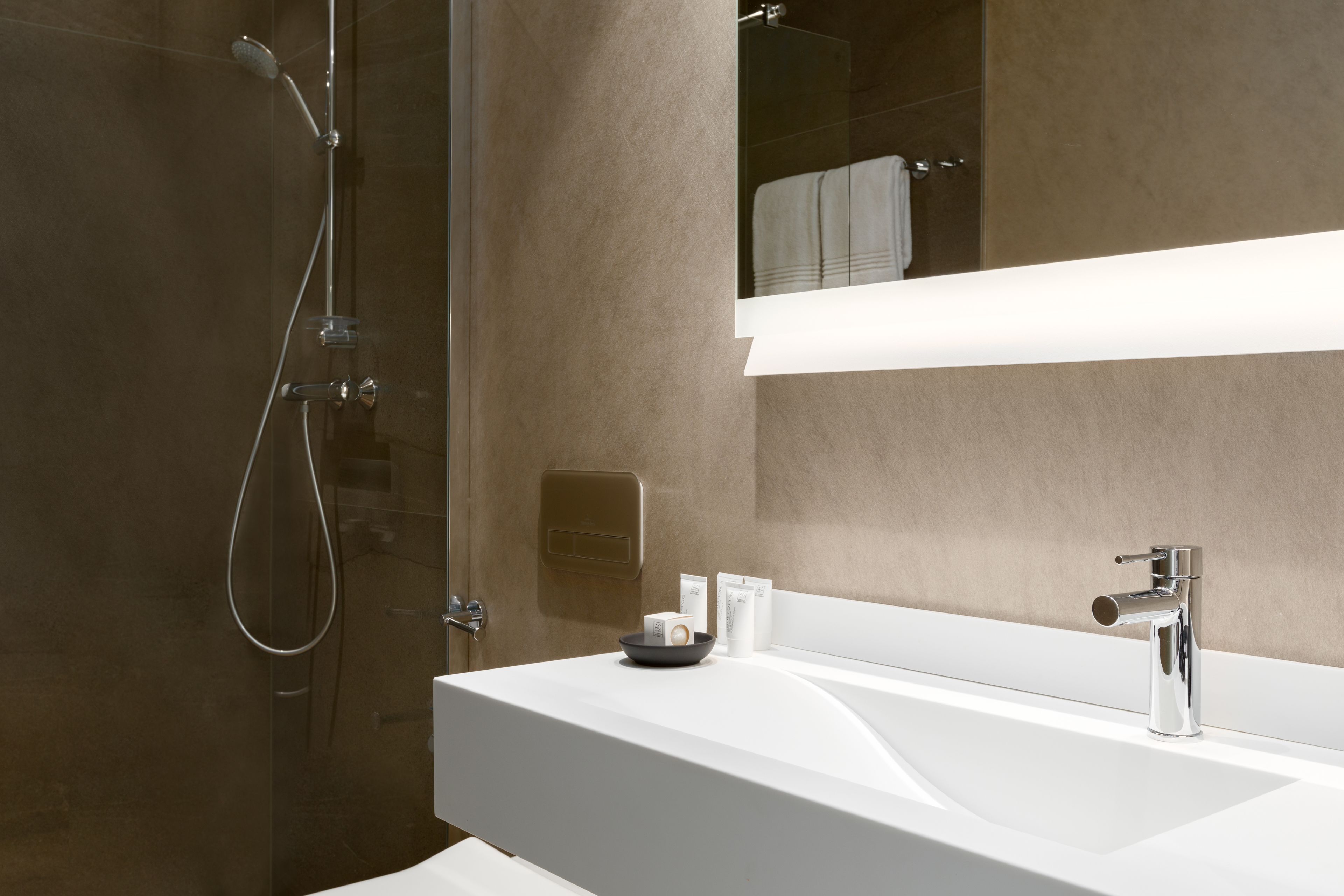 A modern bathroom with a glass-enclosed shower, a white sink, and a large mirror.