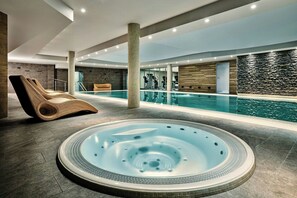 A modern indoor swimming pool area with a hot tub, exercise equipment, and a lounge chair. - AC Hotel by Marriott Wroclaw (Wroclaw)