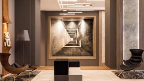 Un lobby moderno con un largo pasillo, sillas contemporáneas y un cuadro abstracto grande.