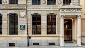 Fachada clásica de un edificio con ventanas arqueadas y una entrada destacada con la inscripción "AC WROCLAW".