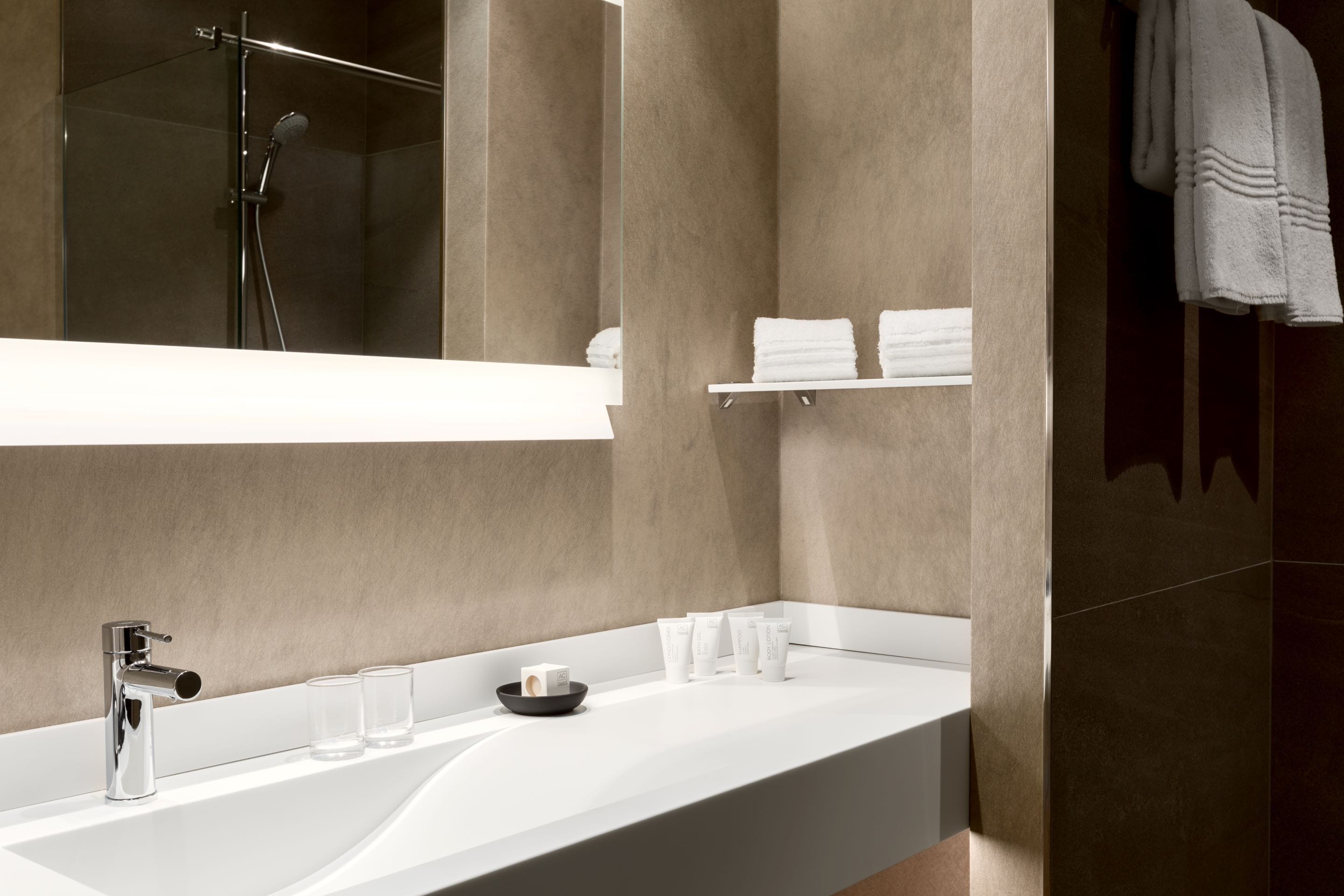 A modern bathroom with a large mirror, a white sink, and a shower area.