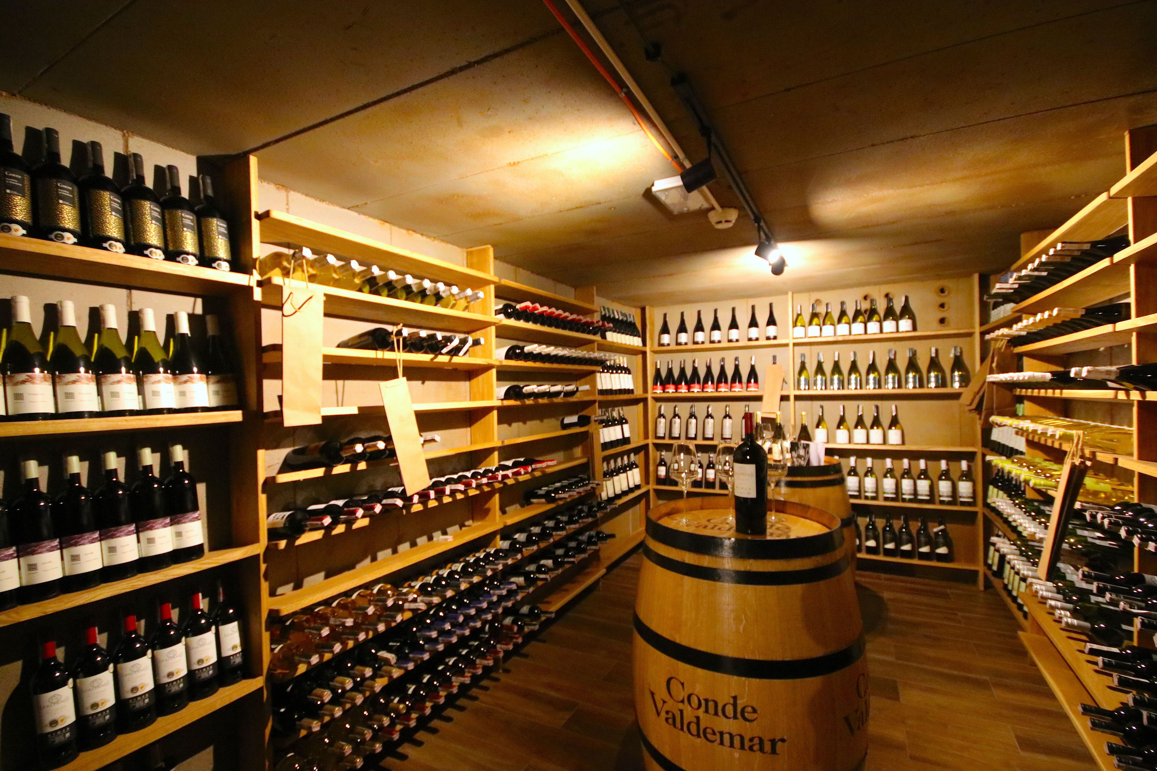 A wine cellar with wooden shelves stocked with various bottles of wine.