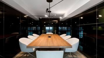 A conference room with a wooden table, white chairs, and modern lighting.