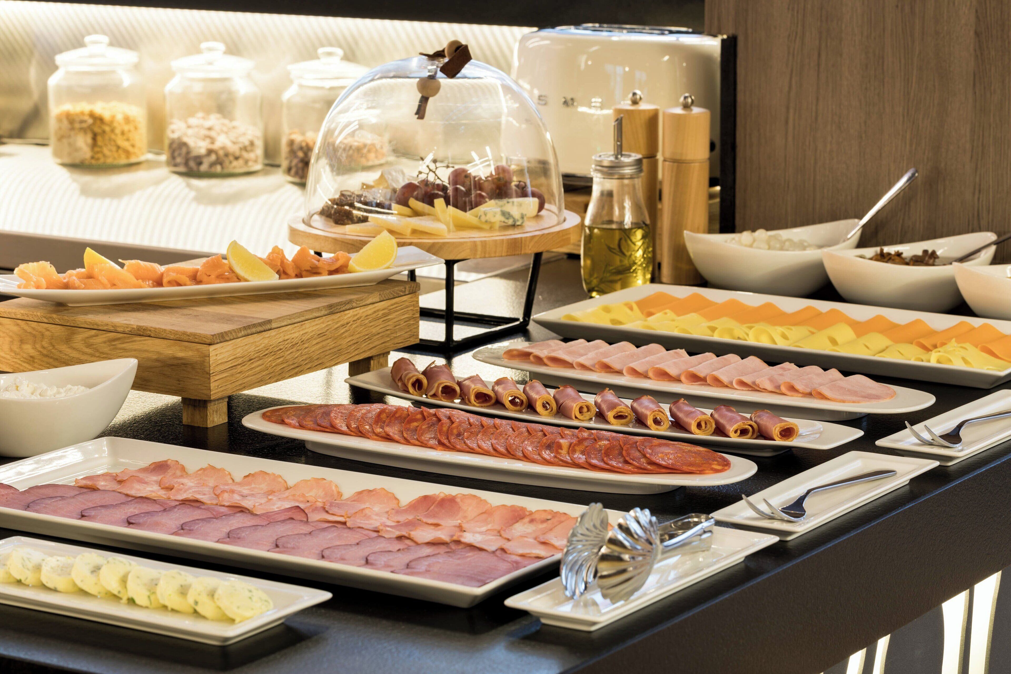 A buffet with various food items including meats, cheeses, and fruits.