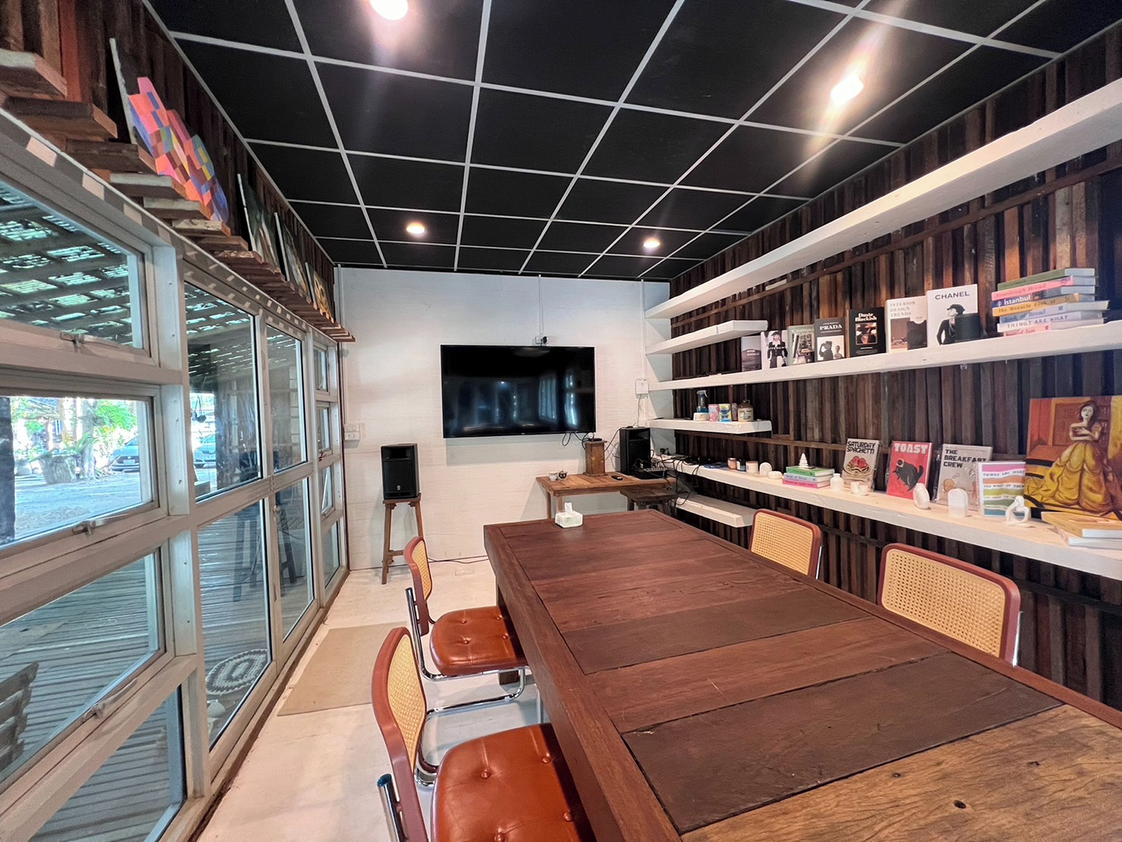 Un interior moderno con una mesa de madera, sillas, una estantería y un televisor.