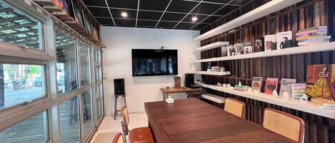 Un interior moderno con una mesa de madera, sillas, una estantería y un televisor.