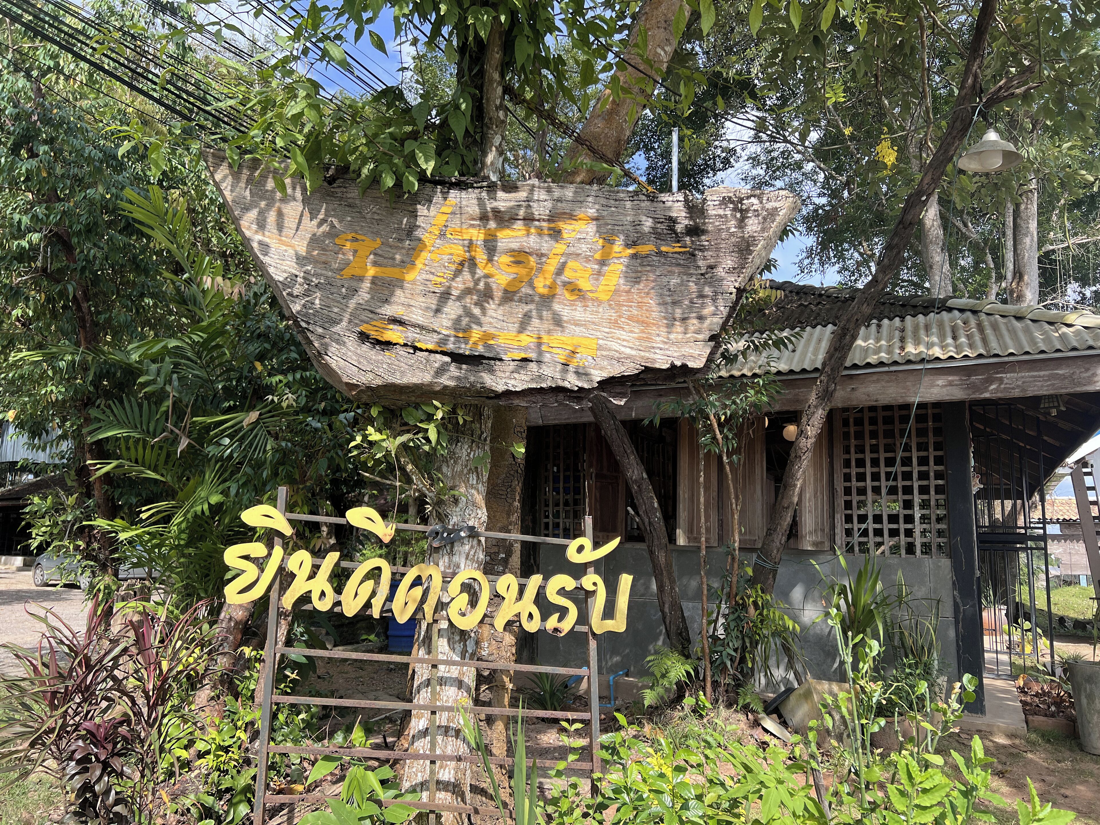 A rustic wooden structure with a weathered signboard and a small building with a corrugated metal roof.