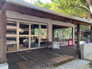 A covered outdoor area with a wooden deck, large windows, and a seating area with tables and chairs. - Pang Mai Resort (Hat Yai)