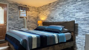 A bedroom with a stone-patterned wall, a wooden bed frame, and a striped bedspread.