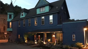 A two-story building with a dark blue exterior, a gabled roof, and a porch area with lights.
