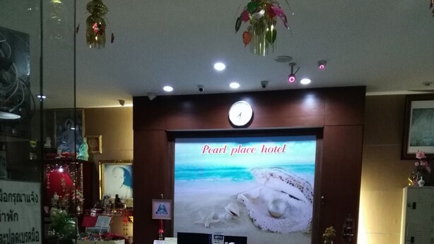 A hotel reception area with a large screen displaying 'Pearl Place Hotel'. - Pearl Place Hotel (Hat Yai)
