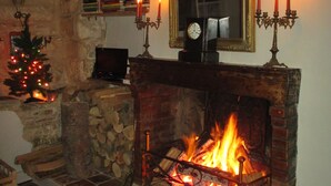Ein gemütlicher Kamin mit Feuer, ein Weihnachtsbaum und ein Spiegel darüber.