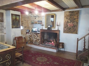 Ein gemütliches Wohnzimmer mit Kamin, einer Holztreppe und einer Chandelier.