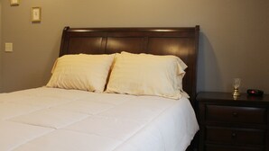 A neatly made bed with a wooden headboard in a hotel room.