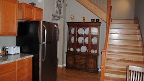 A kitchen with wooden cabinets, a stainless steel refrigerator, and a glass-fronted china cabinet.