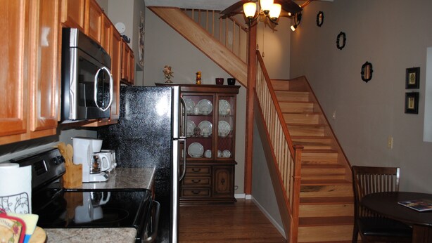 A kitchen with wooden cabinets, a stainless steel refrigerator, a microwave, and a granite countertop.