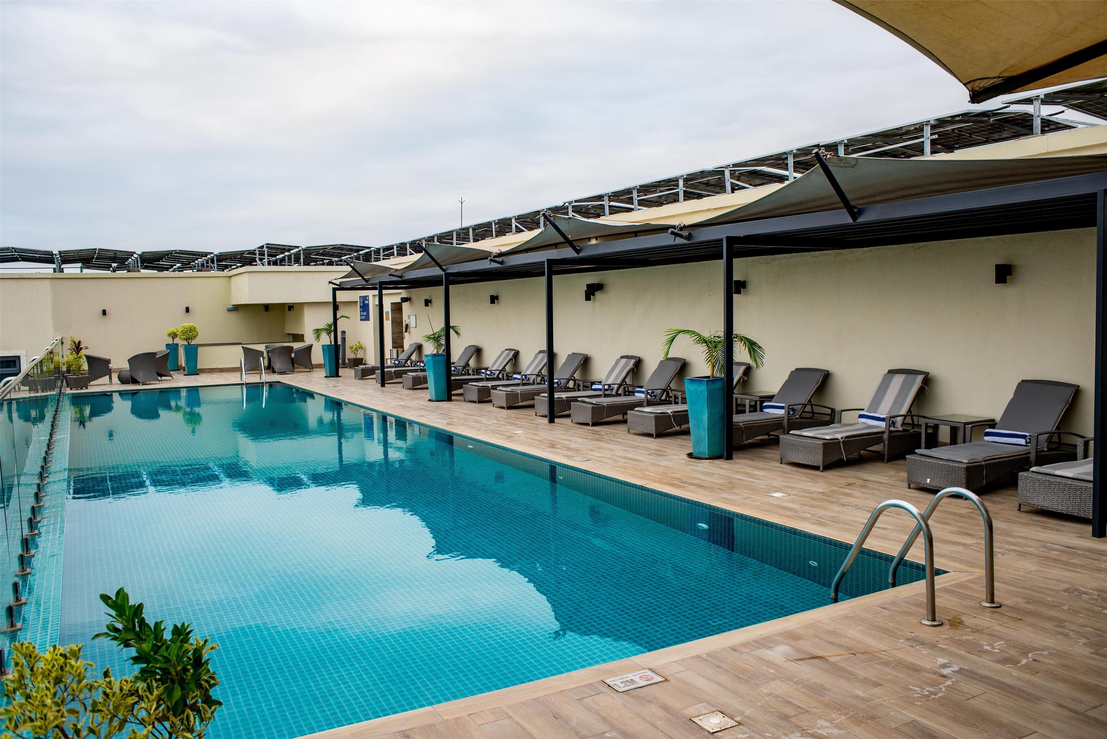 A swimming pool with lounge chairs and umbrellas, surrounded by a wooden deck.