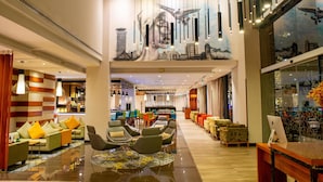 Un lobby moderno con áreas de descanso, un bar y un mural grande.