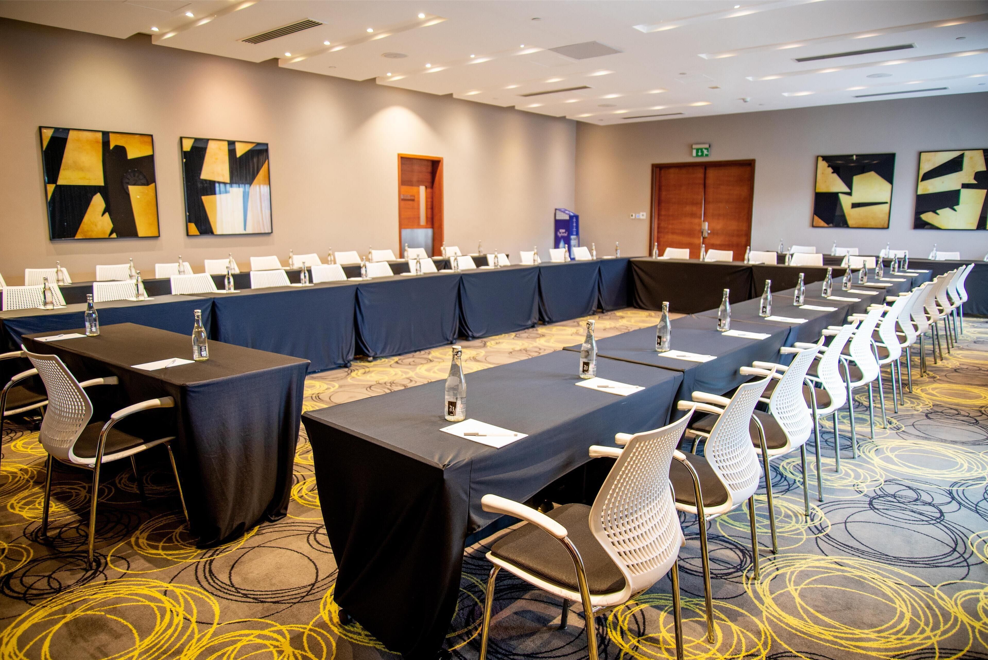 A conference room with long tables, chairs, and water bottles.
