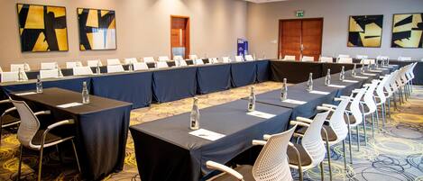 A conference room with long tables, chairs, and water bottles.