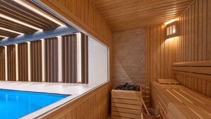 A sauna with wooden walls, a wooden bench, a small wooden bucket, and a stone wall. - Hyatt House Gebze (Gebze)