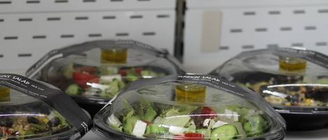 Salad bowls on a shelf with labels indicating different types of salads.