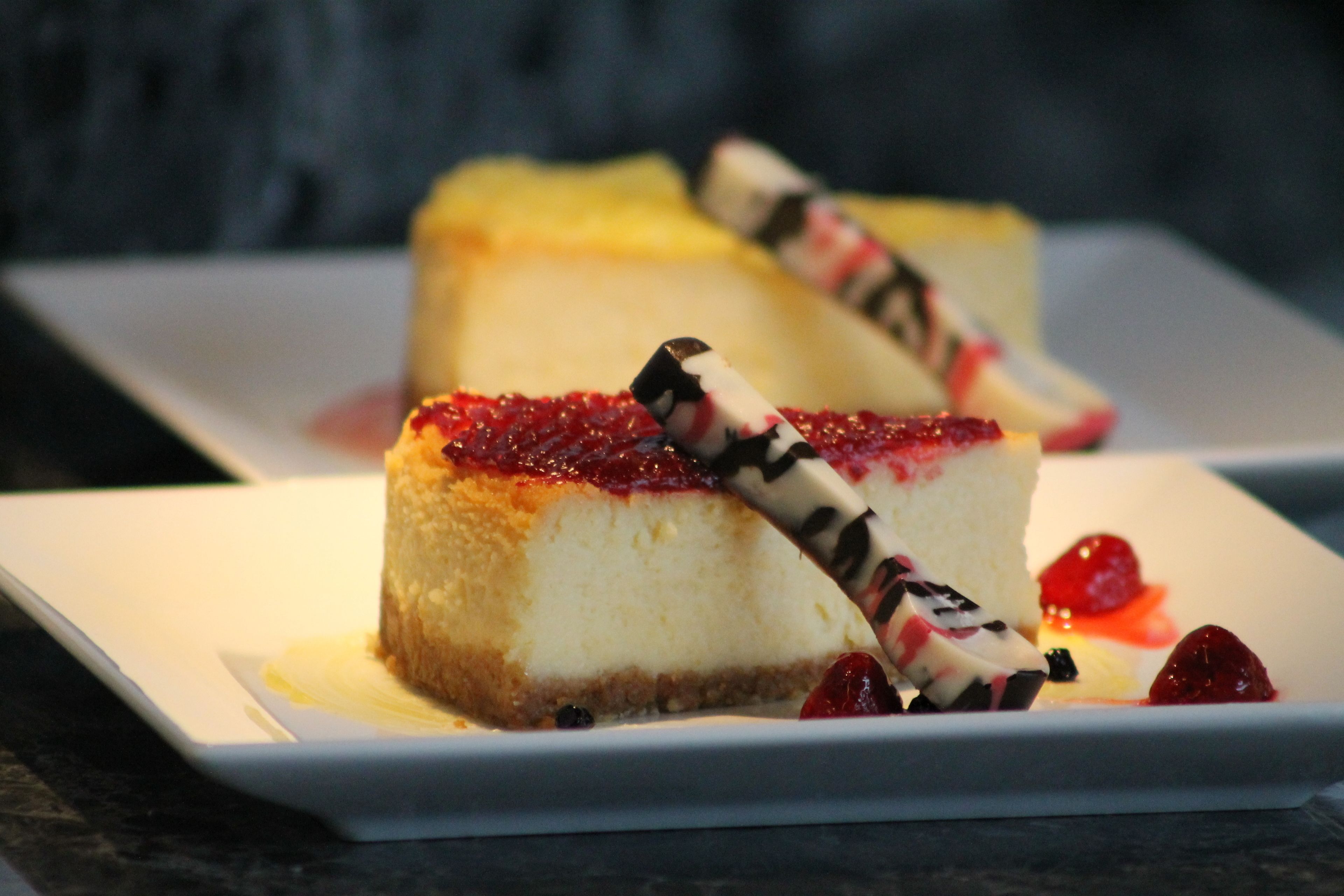 A dessert plate with a slice of cheesecake topped with berries and chocolate shavings.