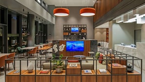 A modern hotel lobby with a reception desk, seating area, and a large TV screen displaying a blue screen. - Hyatt House Gebze (Gebze)