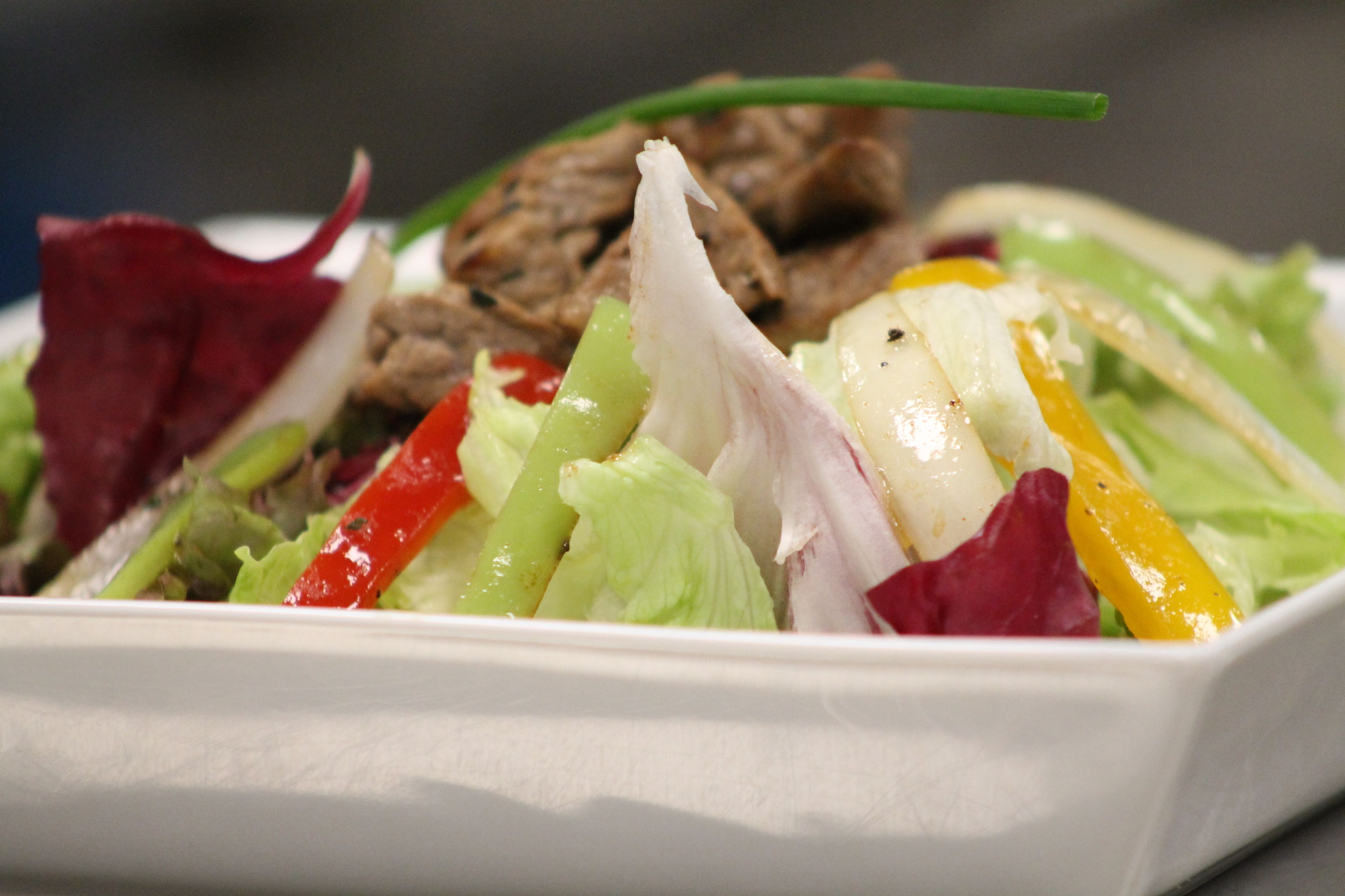 Une vue rapprochée d’une salade composée de divers légumes et de viande.