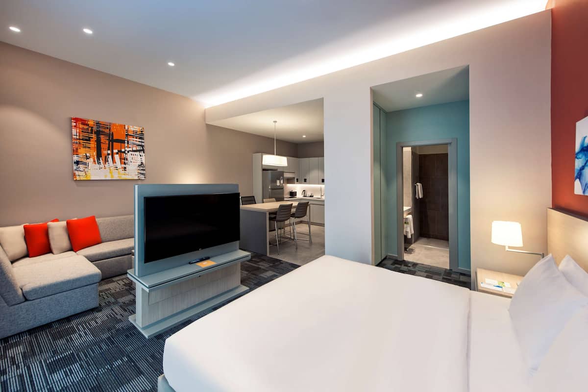 A hotel room with a bed, a TV, a sofa, and a desk area.