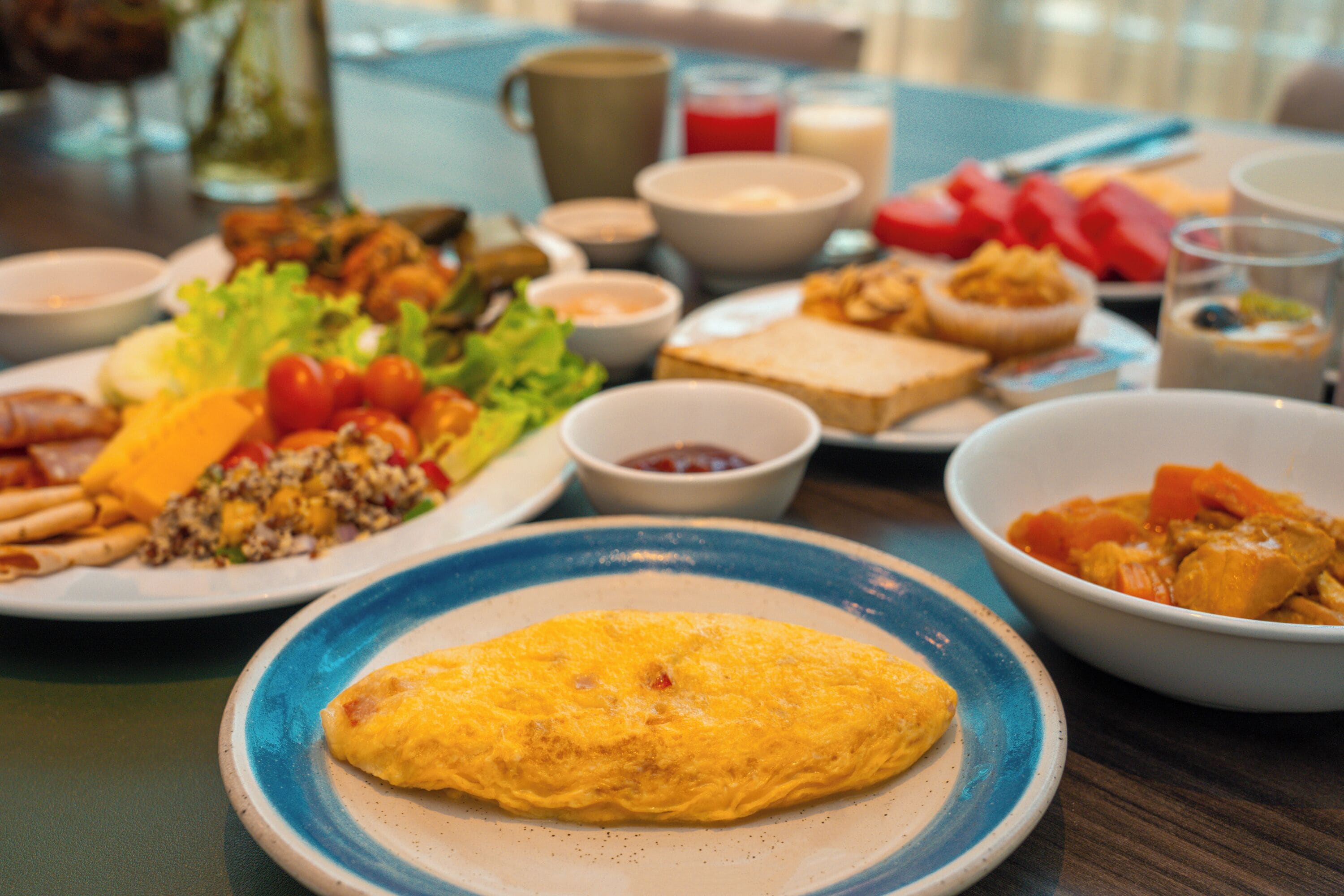 A breakfast spread with various dishes including an omelette, toast, and a bowl of soup.