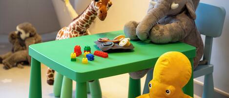 A green table with building blocks, a giraffe, an elephant, and a toy octopus.