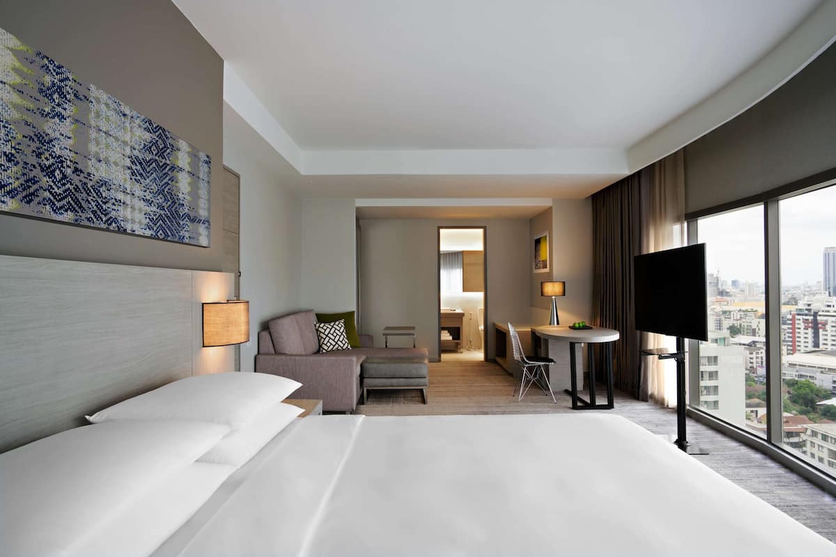 Une chambre d’hôtel moderne dotée d’un grand lit, d’un bureau, d’une télévision et offrant une vue sur la ville.
