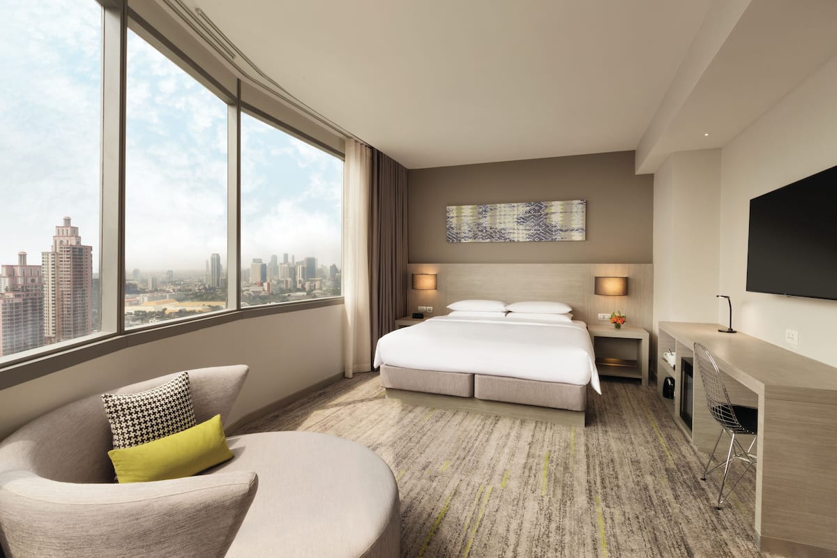 Une chambre d’hôtel moderne équipée d’un grand lit, d’un bureau, d’une chaise, d’un canapé et d’une télévision.