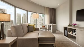 Een moderne hotelkamer met een groot raam, een bank, een klein tafeltje en een televisie.