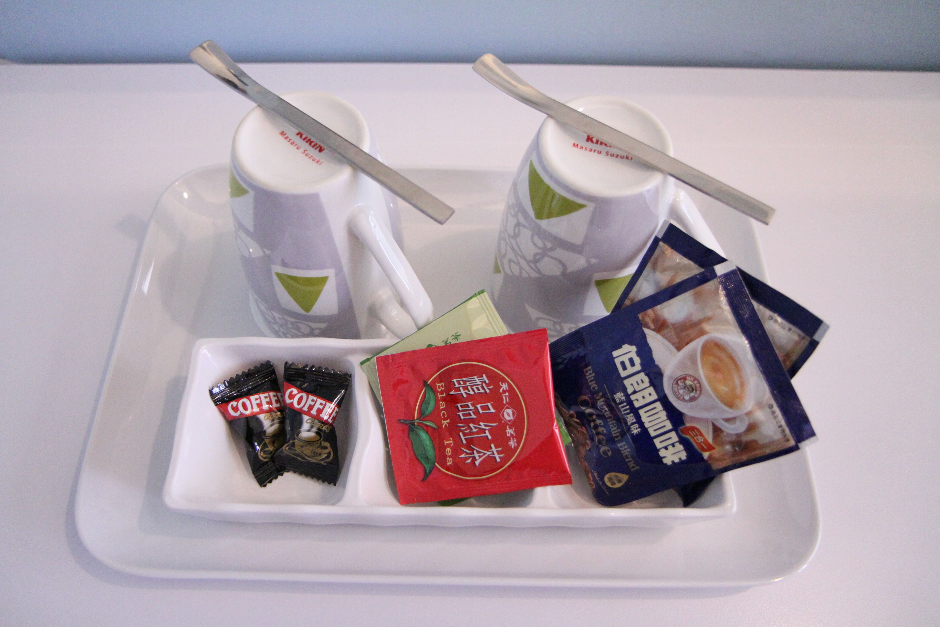 A tray with two coffee mugs, a packet of coffee creamer, and a packet of instant coffee.