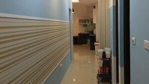 A hallway with a striped wall, a kitchen area in the background, and a cart with bags. - Keyinn Space (Hualien City)
