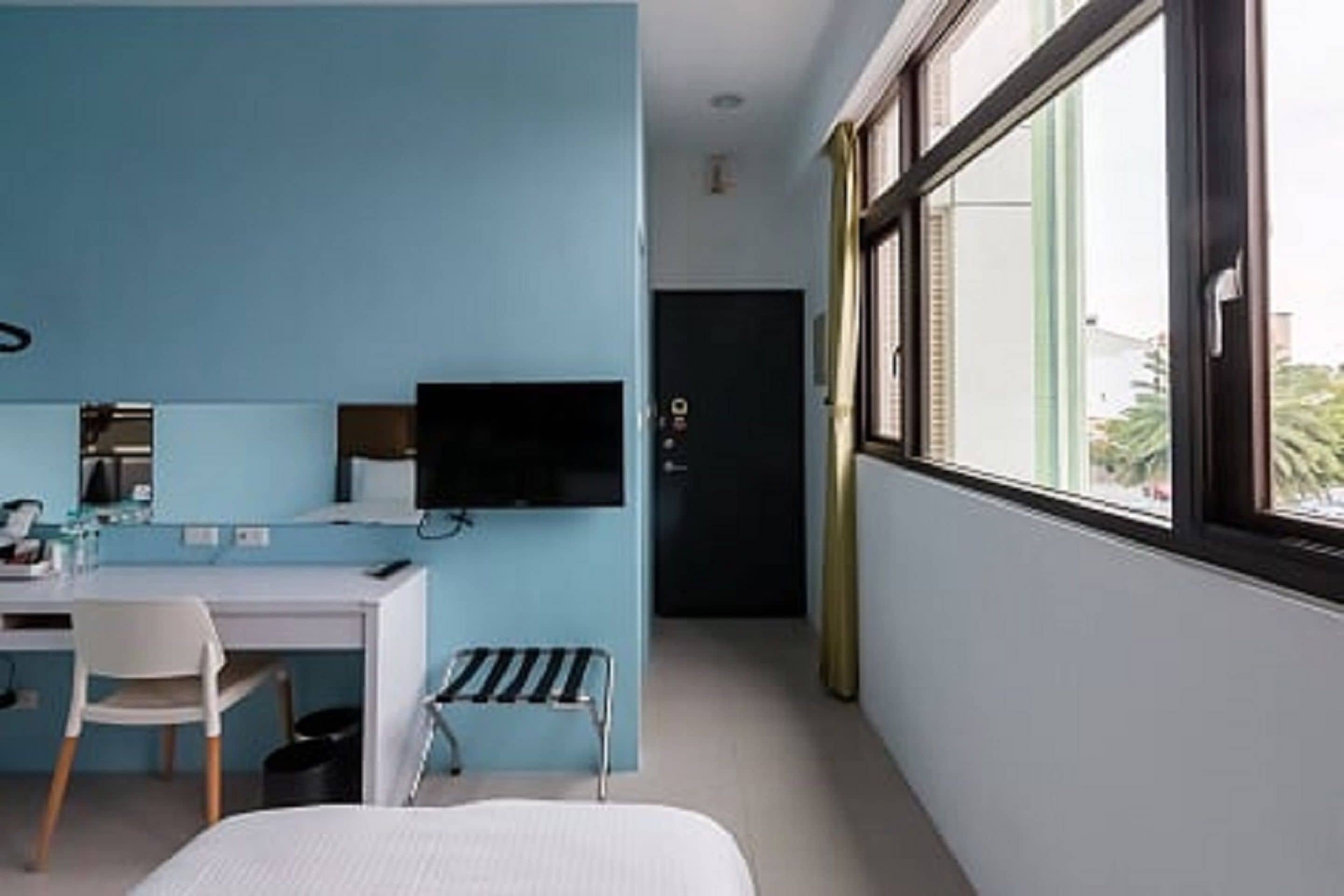 A modern hotel room with a desk, chair, and a bed.