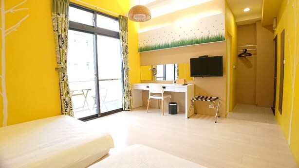 A bright room with yellow walls, a desk, a chair, a bed, and a TV. - Keyinn Space (Hualien City)