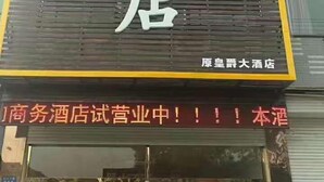 Un letrero de hotel con caracteres chinos y una pantalla digital debajo.