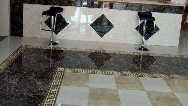 Un área de recepción con mostrador de mármol, dos taburetes de bar y un reloj decorativo en la pared.