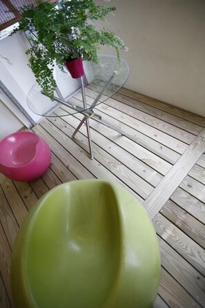 A wooden deck with a glass table and a potted plant.