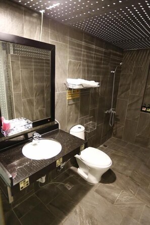 A modern bathroom with a large mirror, a sink, a toilet, and a shower.