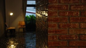 Paredes e chão de tijolos molhados, indicando chuva recente.