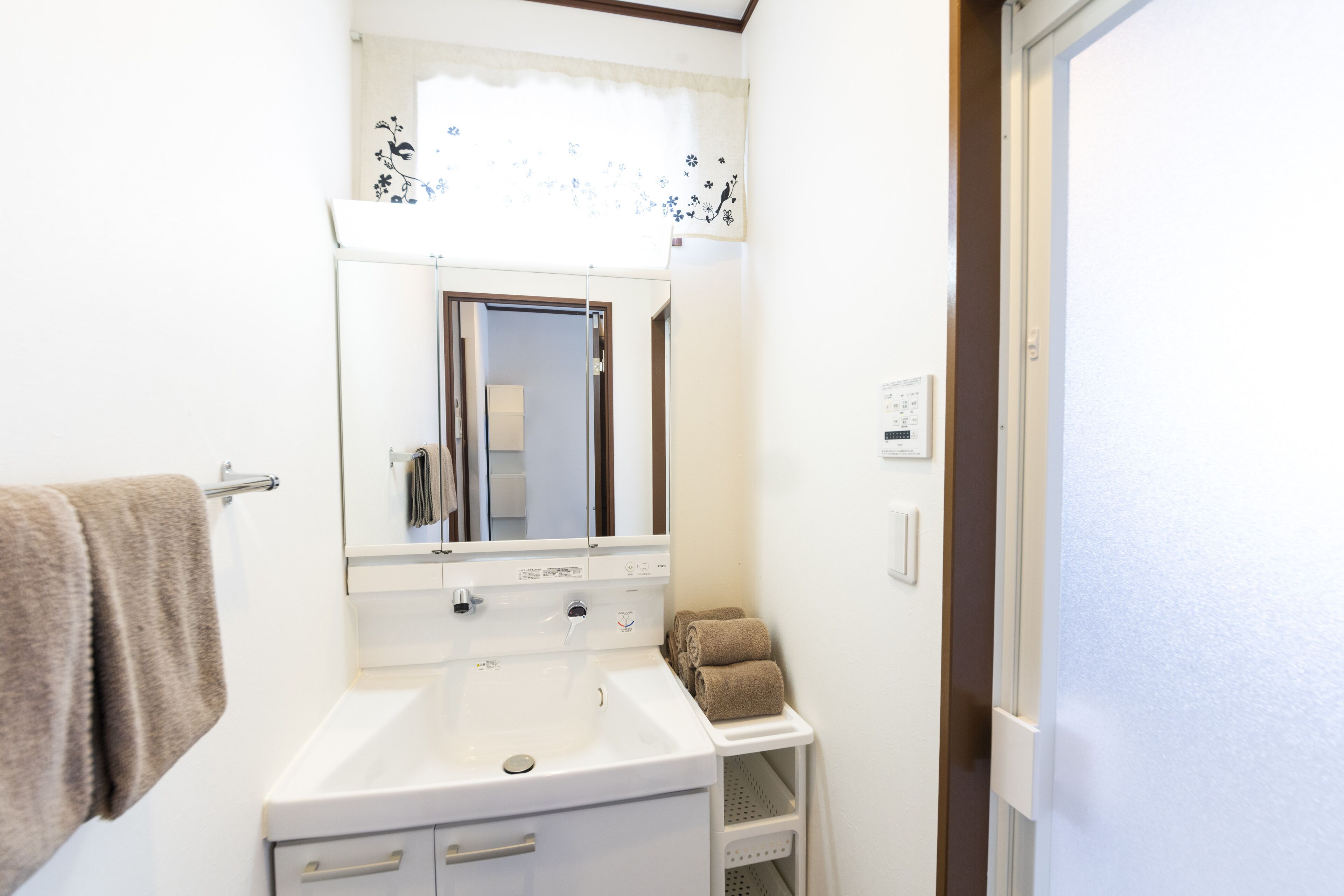 A bathroom with a white sink, a mirror, and a towel rack.