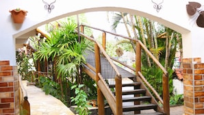 A wooden staircase with a stone pathway leading up to a white wall. - Hotel Britannia (Itatiaia)