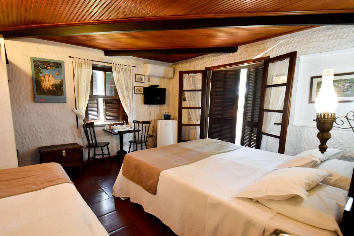 A room with two beds, a desk, a chair, and a television.
