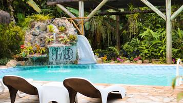 Relax by the serene pool, surrounded by lush greenery and a soothing waterfall.